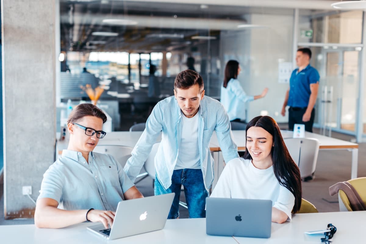 Equipe colaborando ao redor de uma mesa com laptops em ambiente corporativo