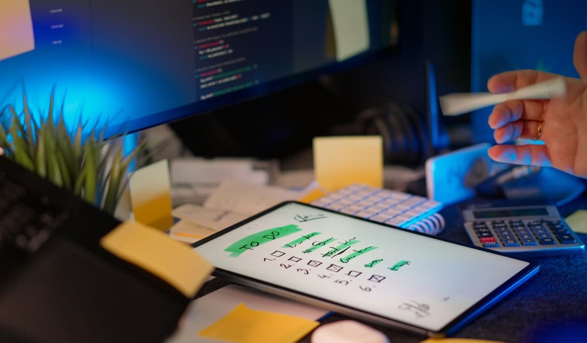 Desenvolvedor trabalhando em múltiplas telas em escritório escuro — ambiente de trabalho tech de alta performance
