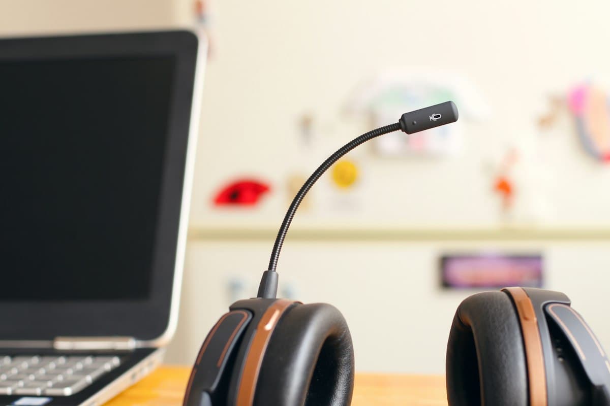 Headset de atendimento ao lado de um notebook em uma mesa de trabalho